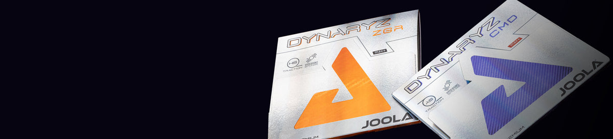Two packages of JOOLA Dynaryz table tennis rubbers in ZGR orange and CMD purple.