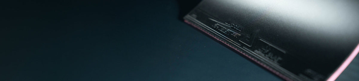 Close-up view of the surface and edge of a black JOOLA table tennis rubber.